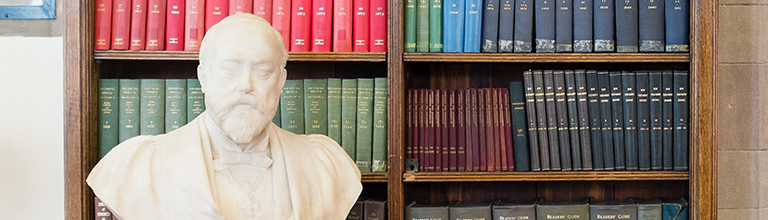A statue bust in front of a shelf full of books
