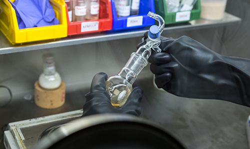 Gloved hands examining chemical engineering apparatus